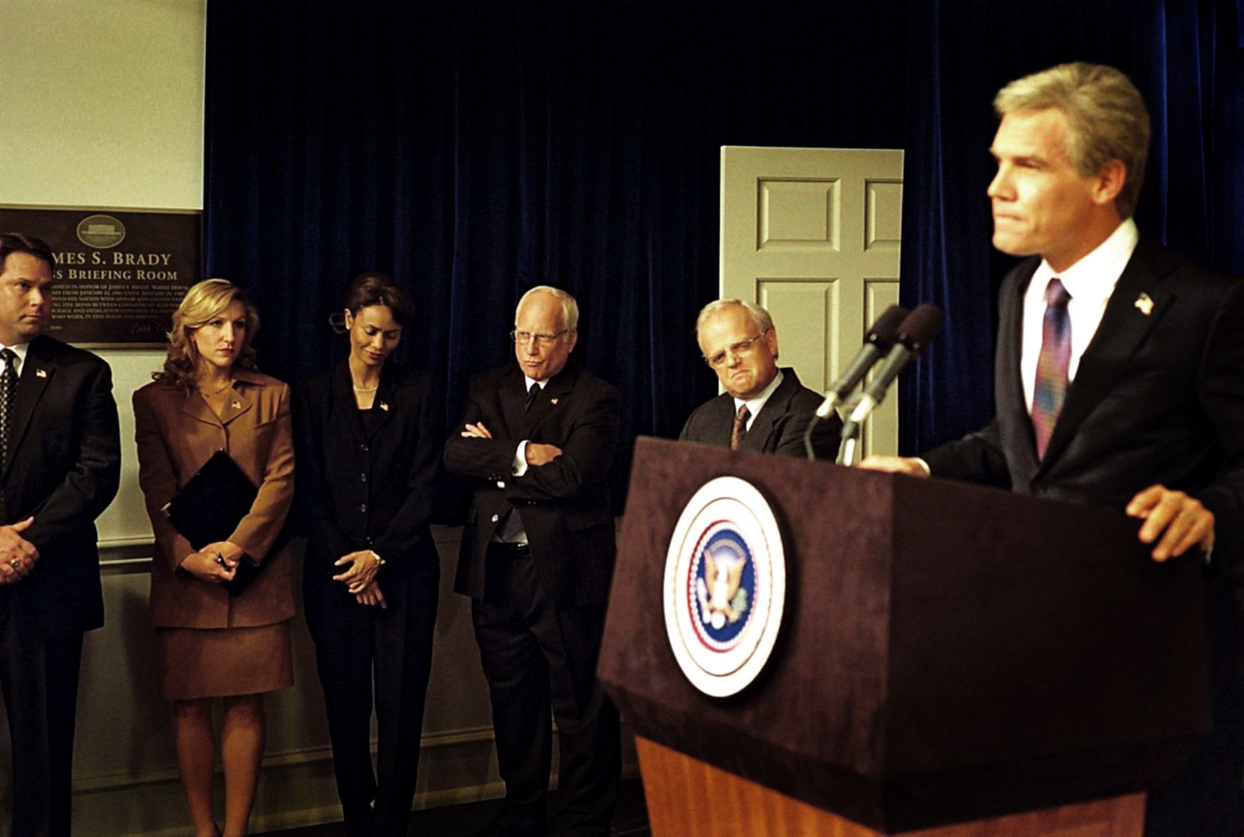 The cast of W. watching as Josh Brolin as George Bush speaks at a podium