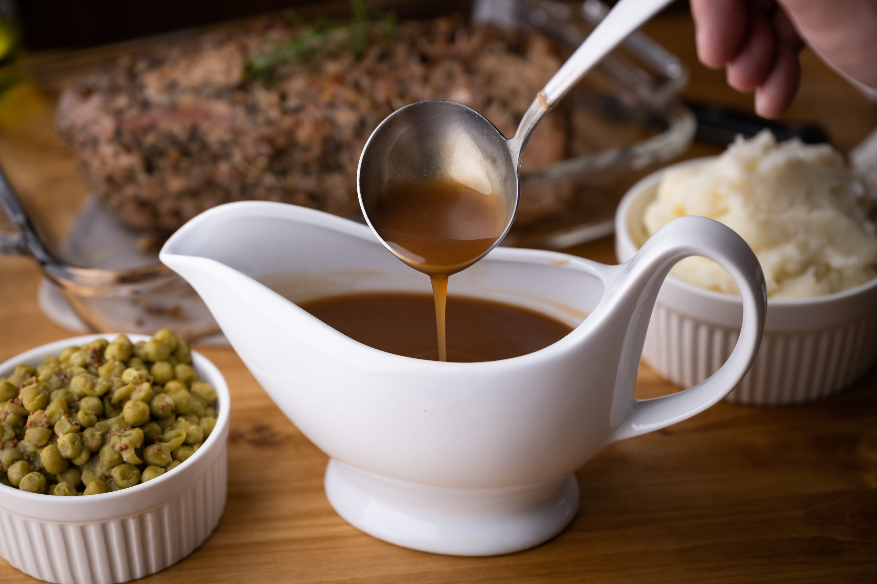 a ladle and gravy tray with brown gravy inside