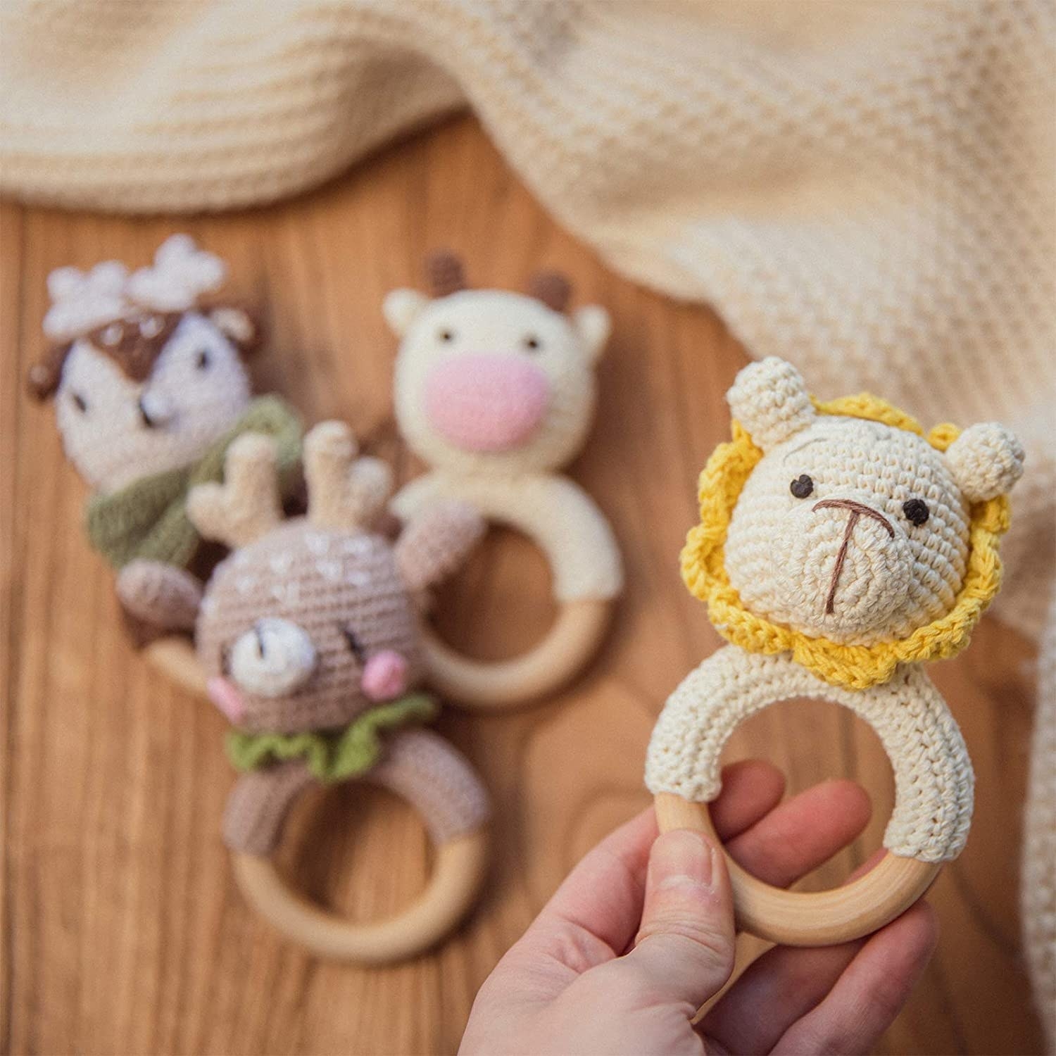 person holding the knitted lion rattle with several others out of focus below it