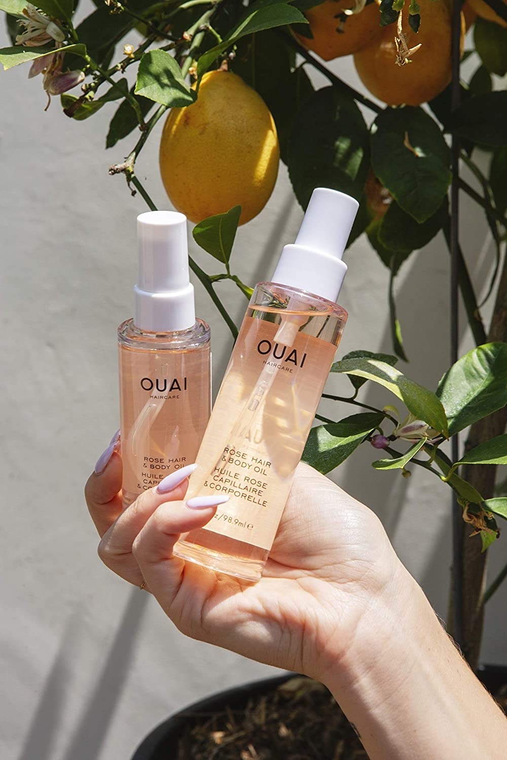 a hand holding two bottles of ouai hydrator