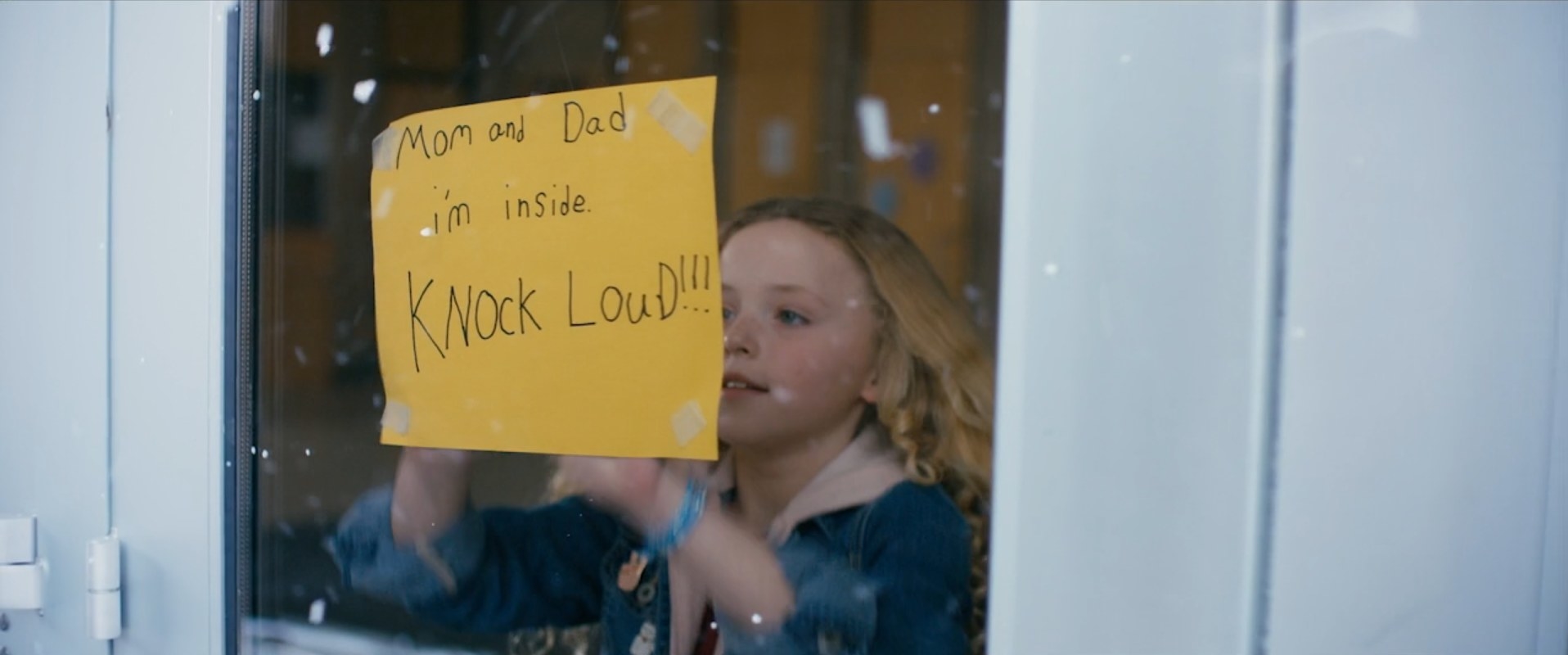 A girl sticks a notice on the glass portion of a door of her school