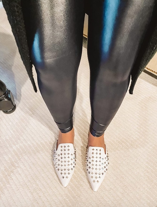 Reviewer wearing white, silver studded, pointed mules with black pants