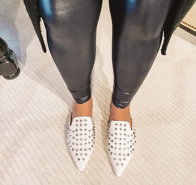 Reviewer wearing white, silver studded, pointed mules with black pants