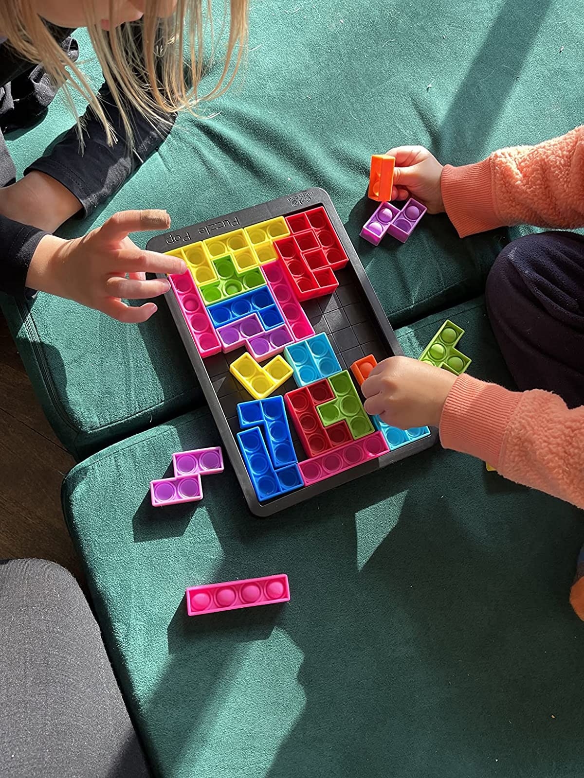 Reviewer&#x27;s photo of children playing with colorful puzzle popper game pieces