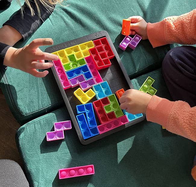 Reviewer's photo of children playing with colorful puzzle popper game pieces