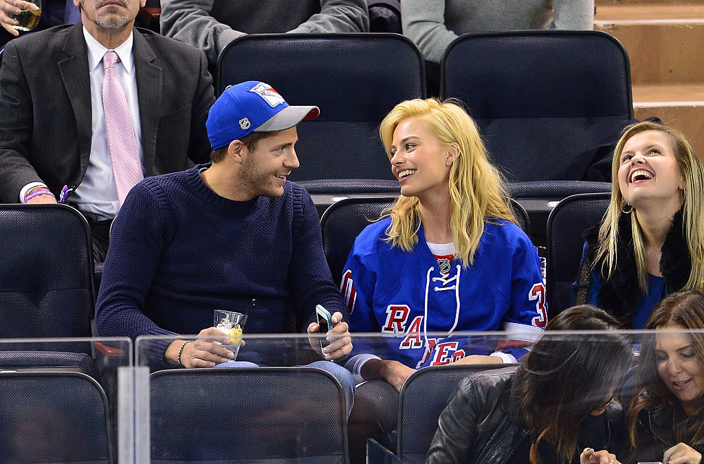 Tom Ackerley and Margot Robbie smile at each other in the stands at the Philadelphia Flyers vs New York Rangers game