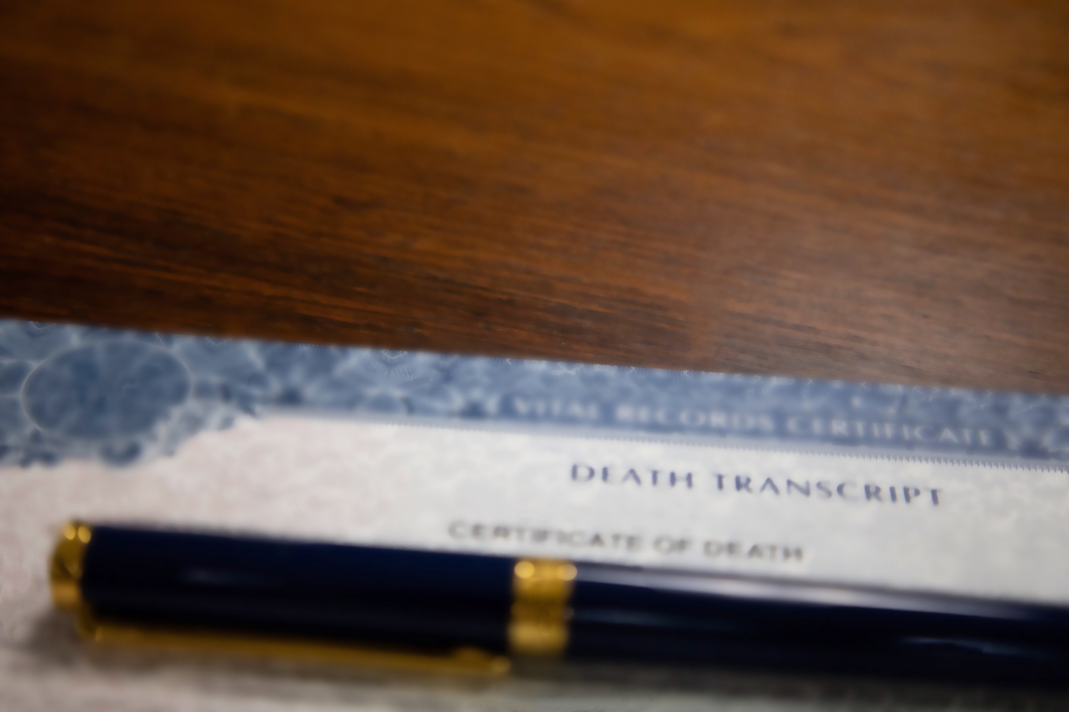 A certificate of death on a table with a pen on top of it