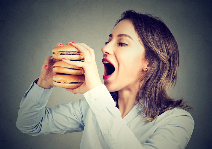 woman eating 3 burgers