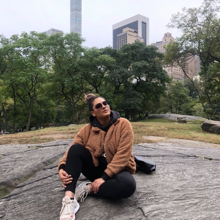 reviewer in brown hip-length coat styled with black leggings and white sneakers