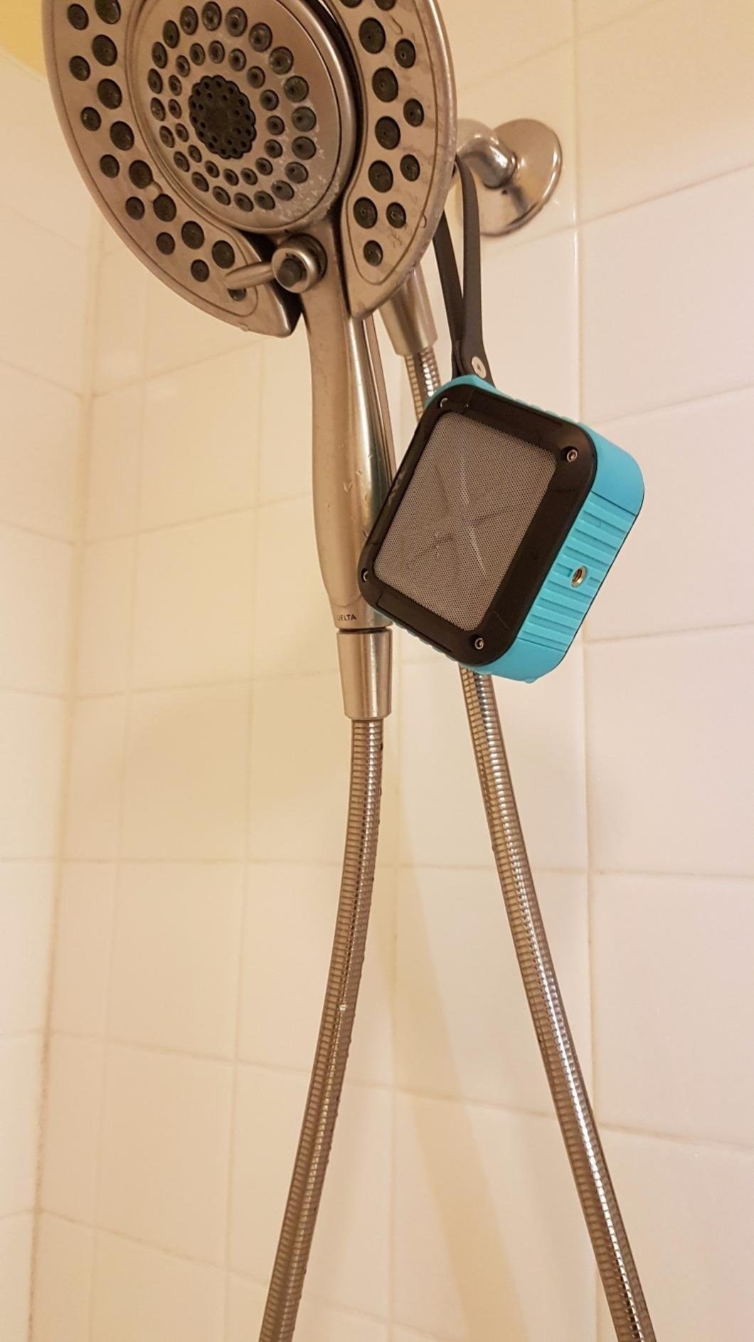 blue speaker hanging on a shower head