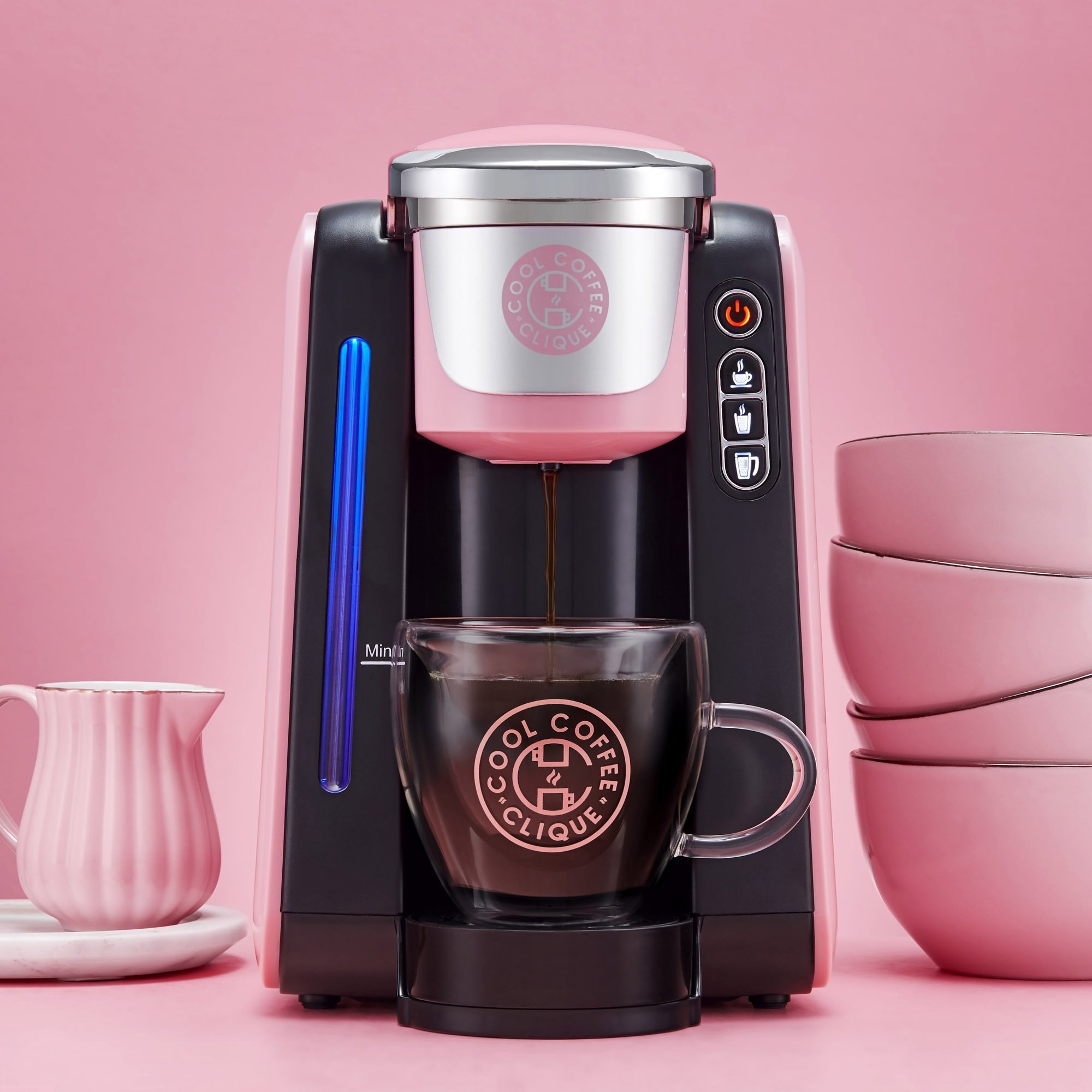 A black and pink coffee machine pouring coffee into a glass mug