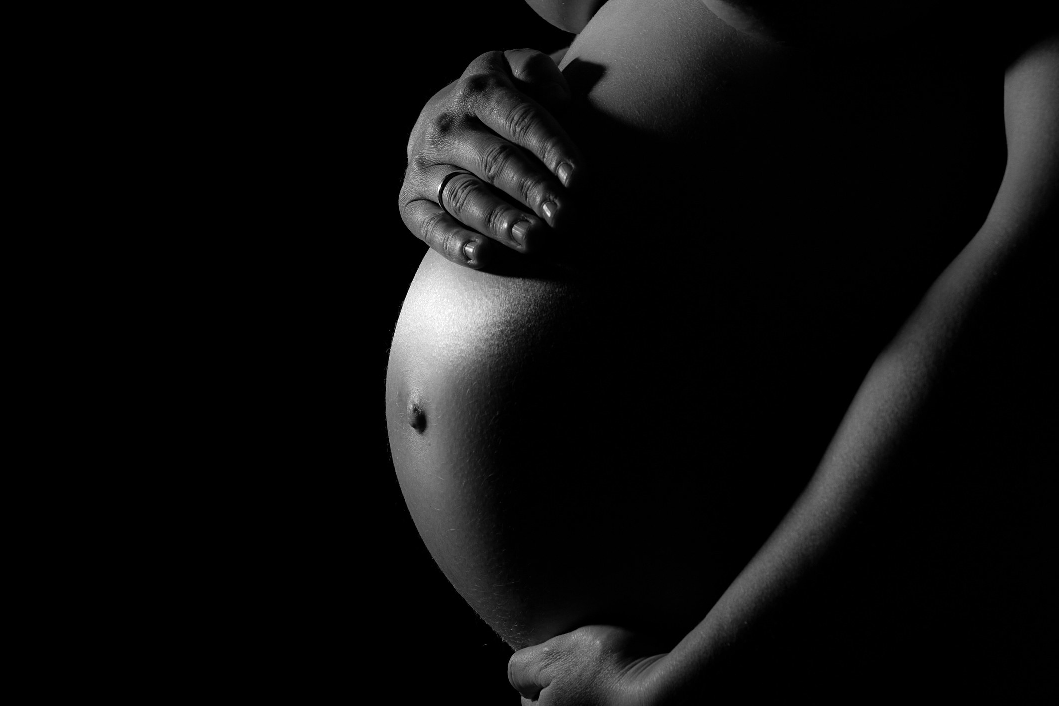A black-and-white image of a pregnant belly being held by two hands