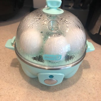 reviewer's photo of the egg cooker in teal cooking eggs