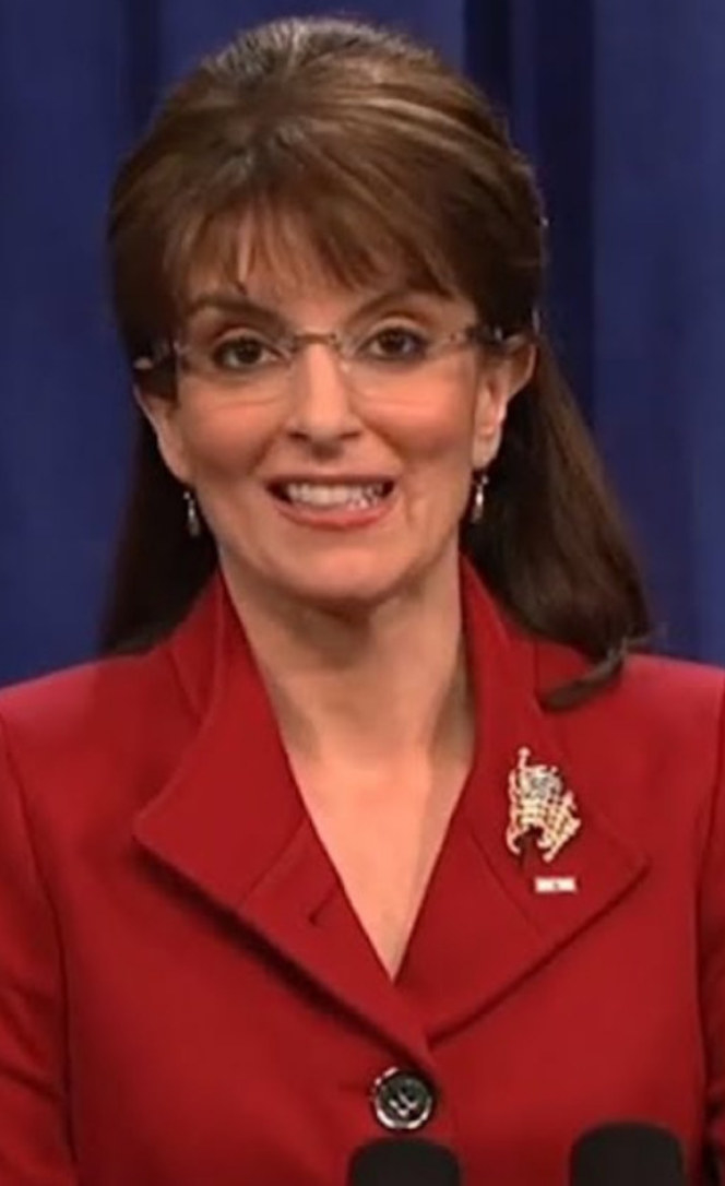 Fey wearing a bright colored suit, glasses, pulled back hair with bangs