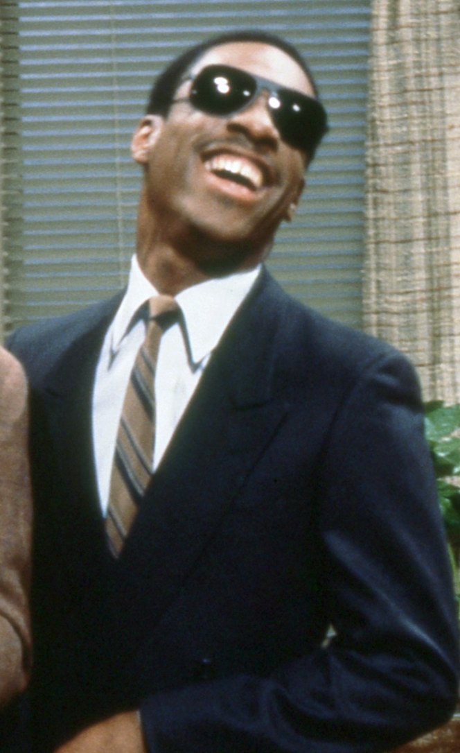 Murphy wearing a suit and tie, glasses, smiling happily