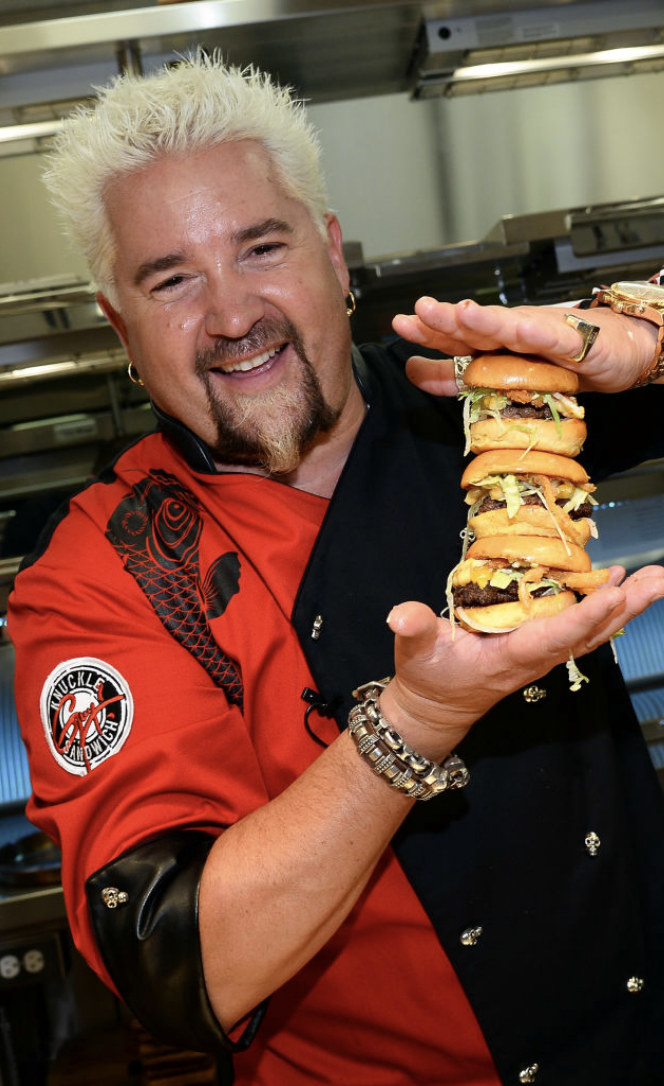 Fieri holding a stack of burgers in the mid-2010s