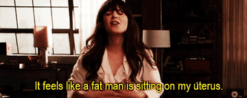 Jessica from New Girl is holding her stomach and shouting.