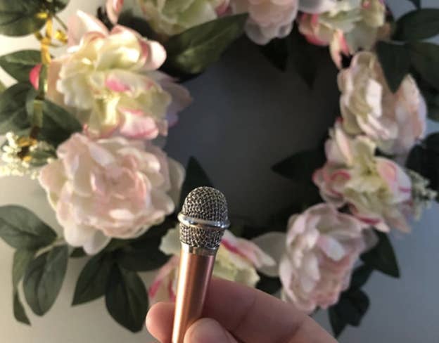 hand holding up tiny microphone in front of a wreath