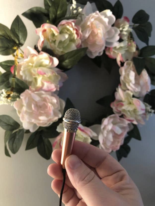 hand holding up tiny microphone in front of a wreath