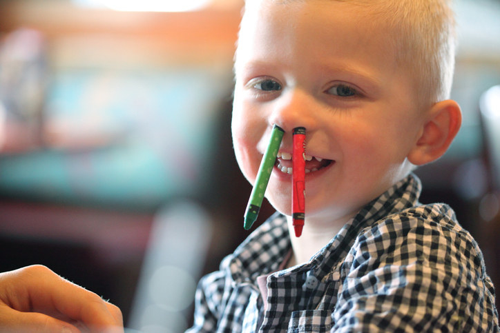 A child with two crayons stuck up their nostrils