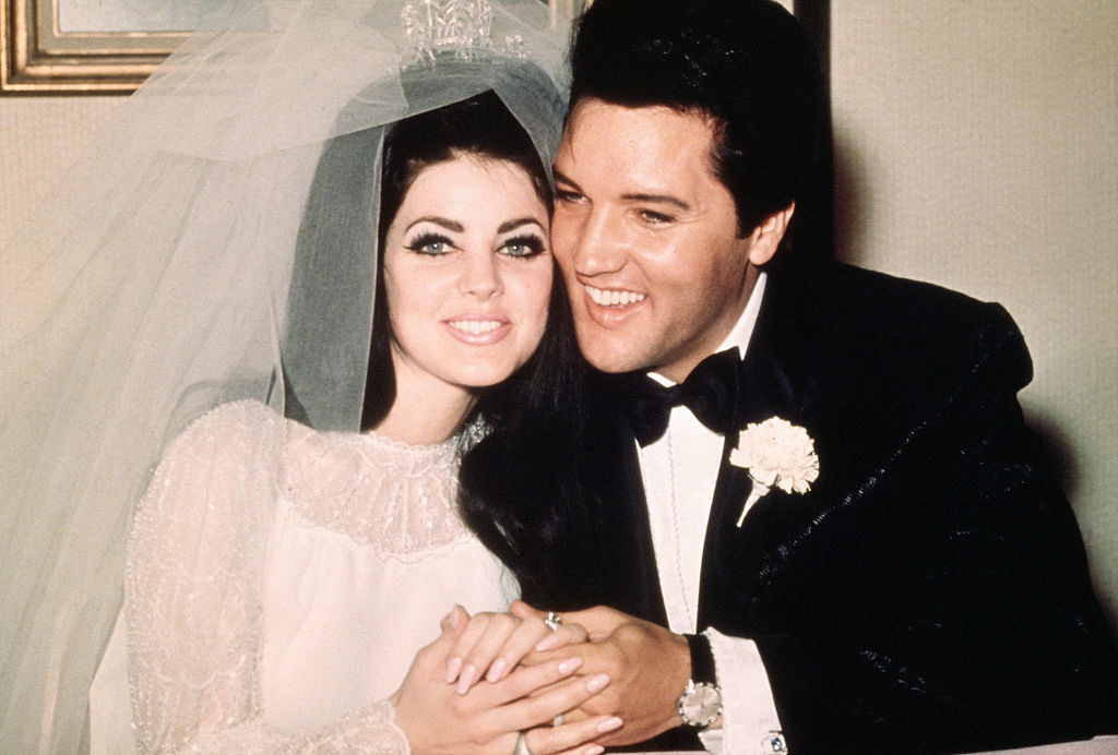 Elvis and Priscilla Presley holding hands at their wedding