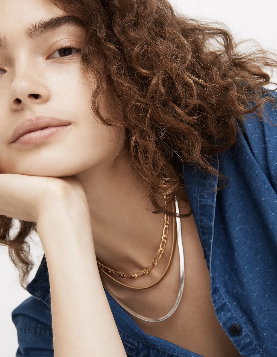 Model wearing both the gold and silver chain necklaces with another gold twisted chain necklace