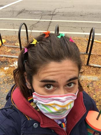 reviewer wearing six of the clips in their hair with a rainbow mask