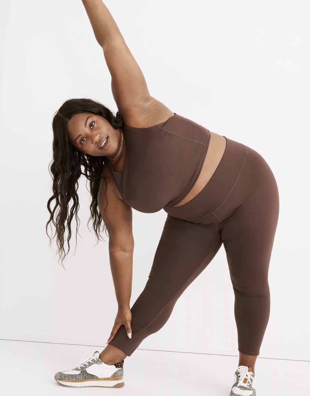 Model stretching in the brown leggings with matching crop top
