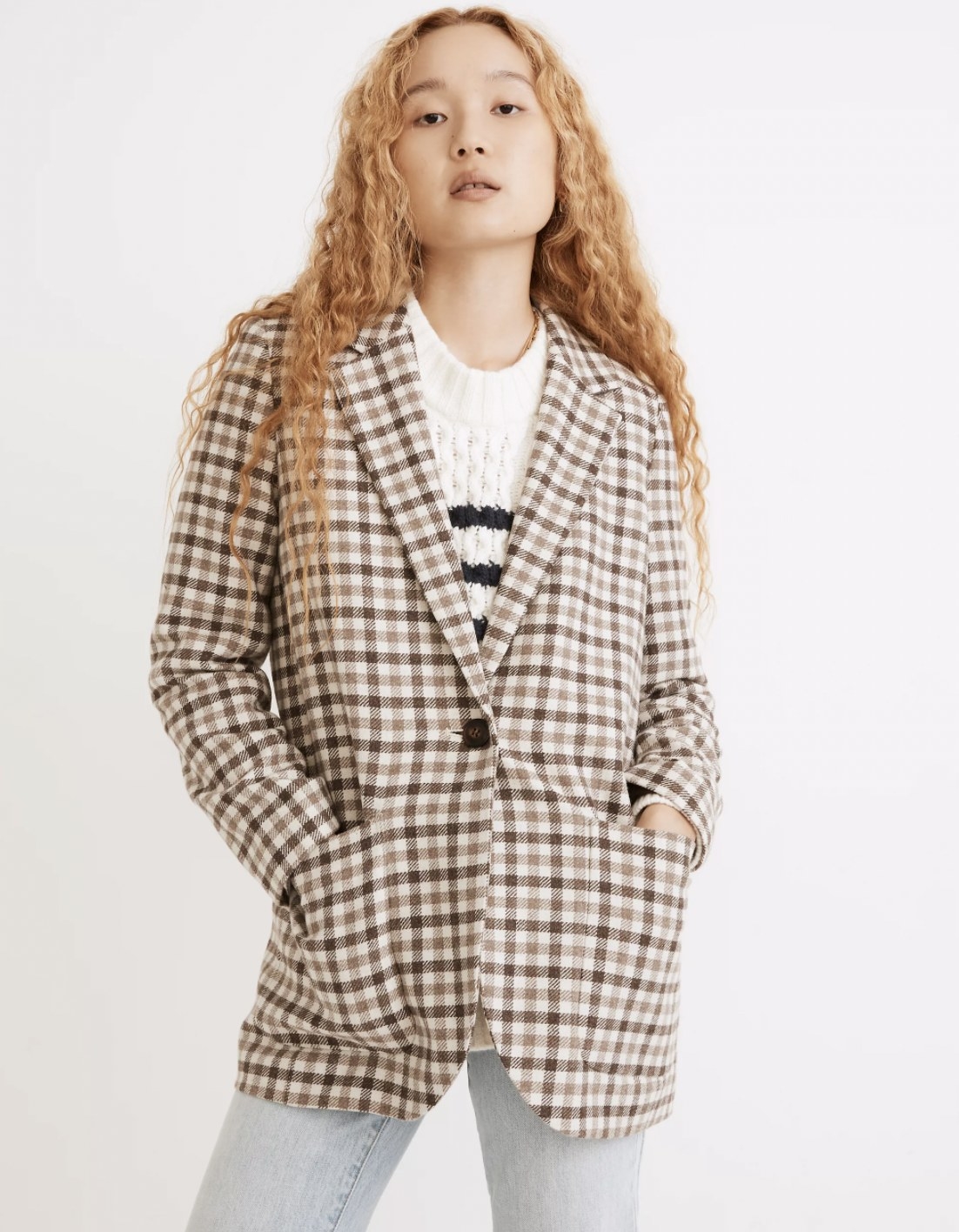 Model wearing the neutral-toned checkered blazer over a sweater with jeans