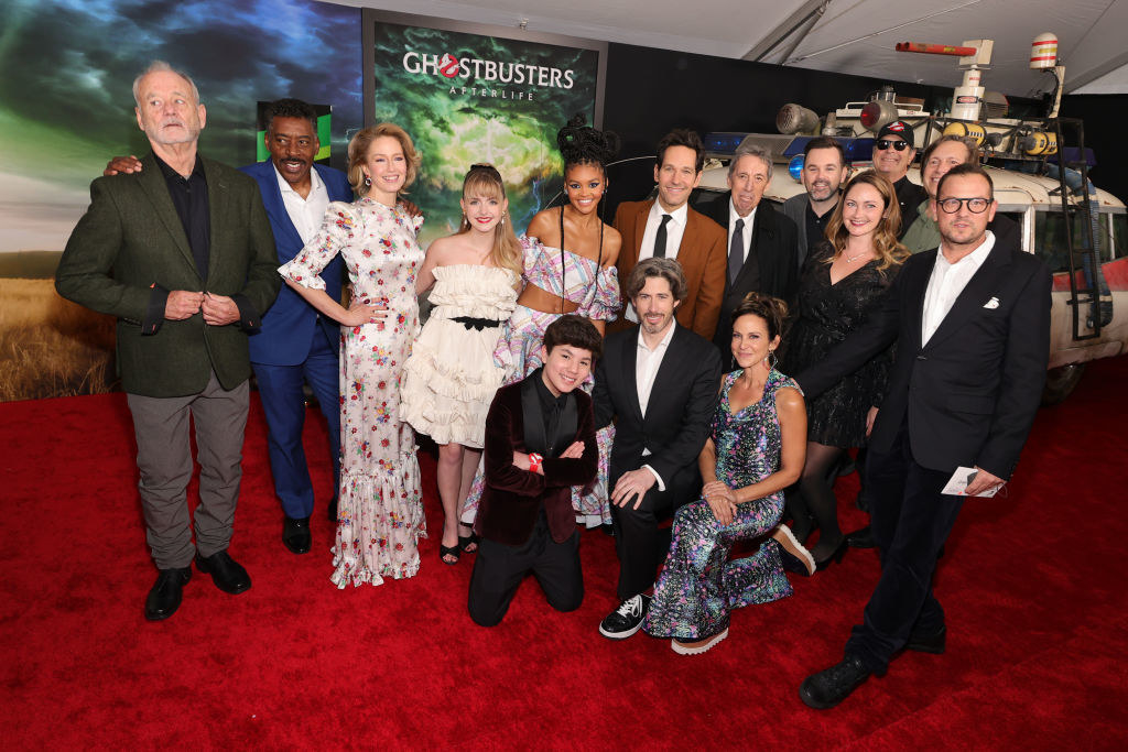 Group picture with people wearing suits, and dresses and fancy clothes on a red carpet for Ghostbusters movie.