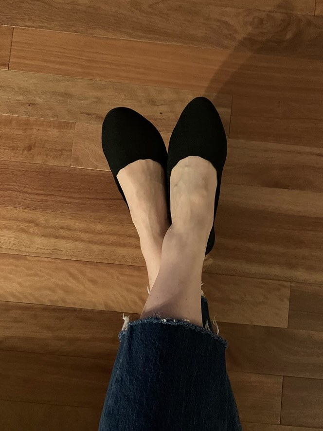A reviewer wearing a black pair of flats with jeans