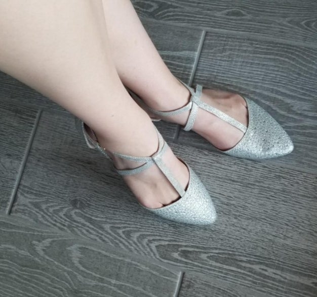 A reviewer wearing silver flats with straps