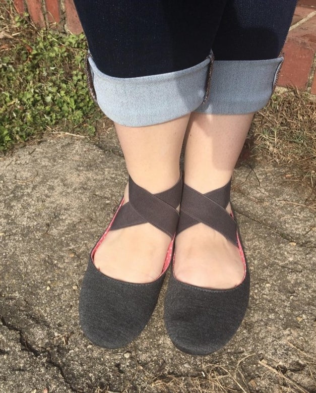 A reviewer wearing black flats with straps outside with jeans