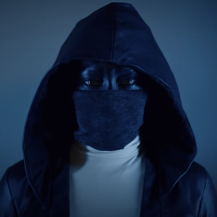 A woman in a good with a mask pulled over her face, up to her piercing eyes