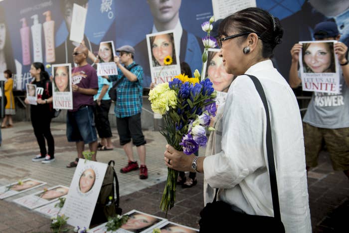 People hold flowers and photos of Heather Heyer with the caption &quot;let us all unite&quot;