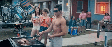 Man with no shirt on cooks on the BBQ