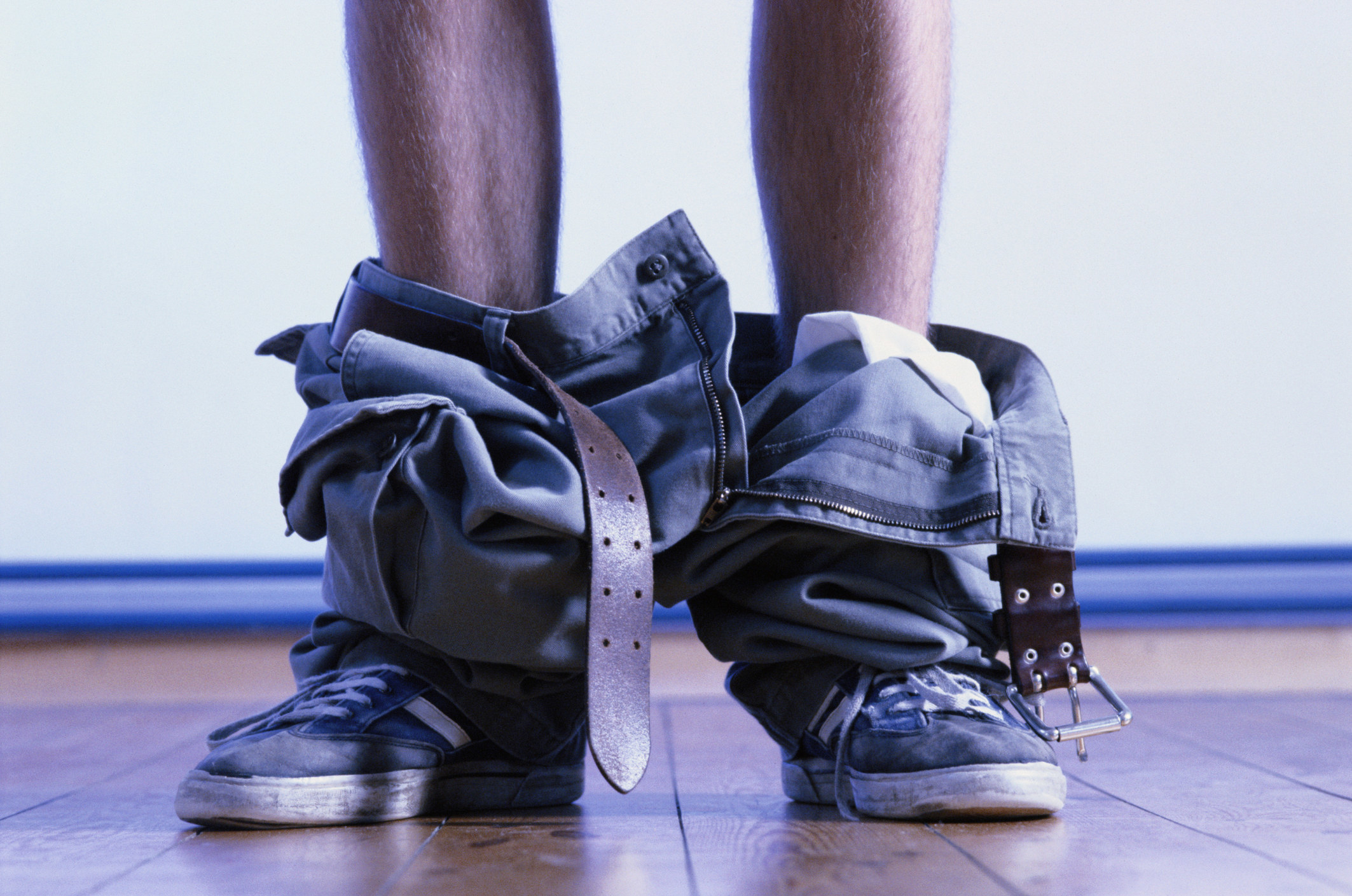 Someone stands with their pants around their ankles, like they're about to pee