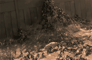 GIF of a horde of people trying to climb a hill of rubble