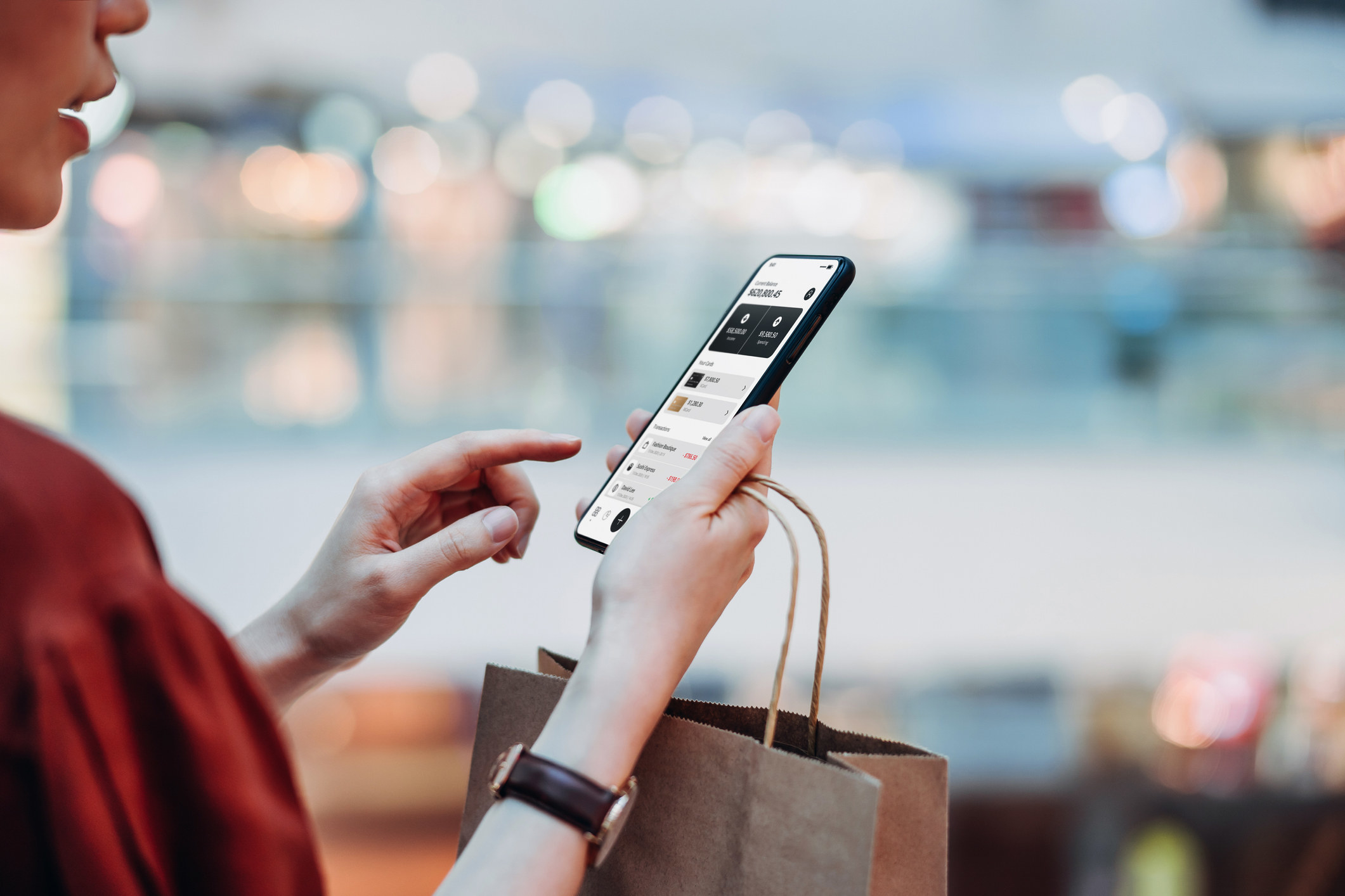 A woman holding a paper shopping bag, managing online banking