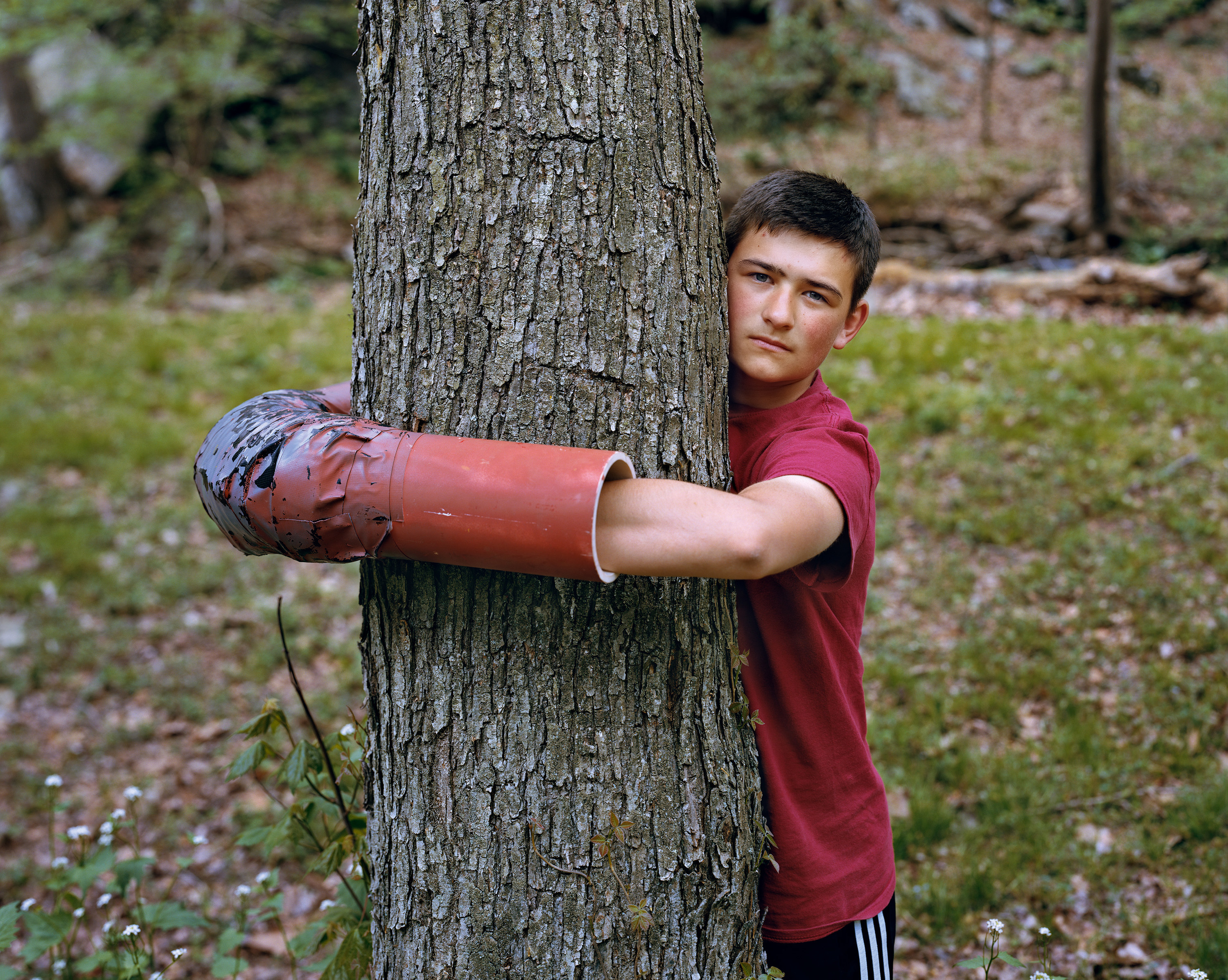 Mitch Epstein, &quot;Ashton Clatterbuck, Lancaster County, Pennsylvania,&quot; showing a young man standing and embracing a tree trunk