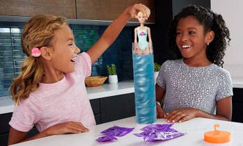two children dipping barbie into the color changing water