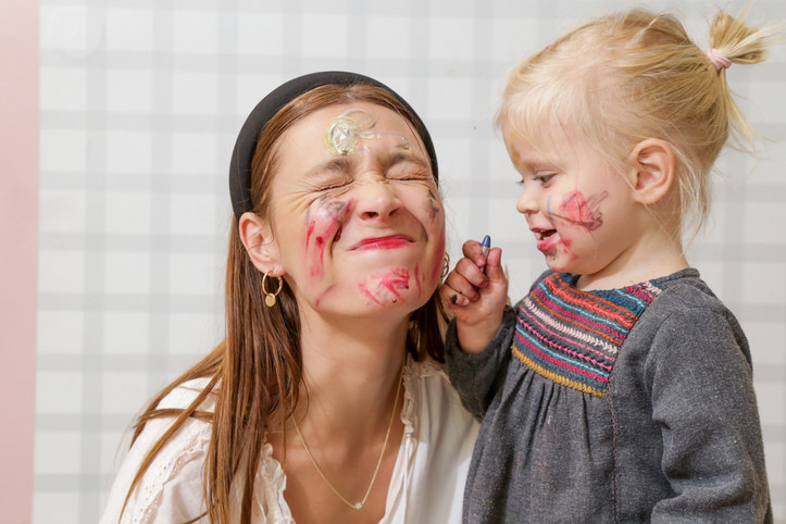A small kid drawing on her face and the babysitter&#x27;s dace with lipstick