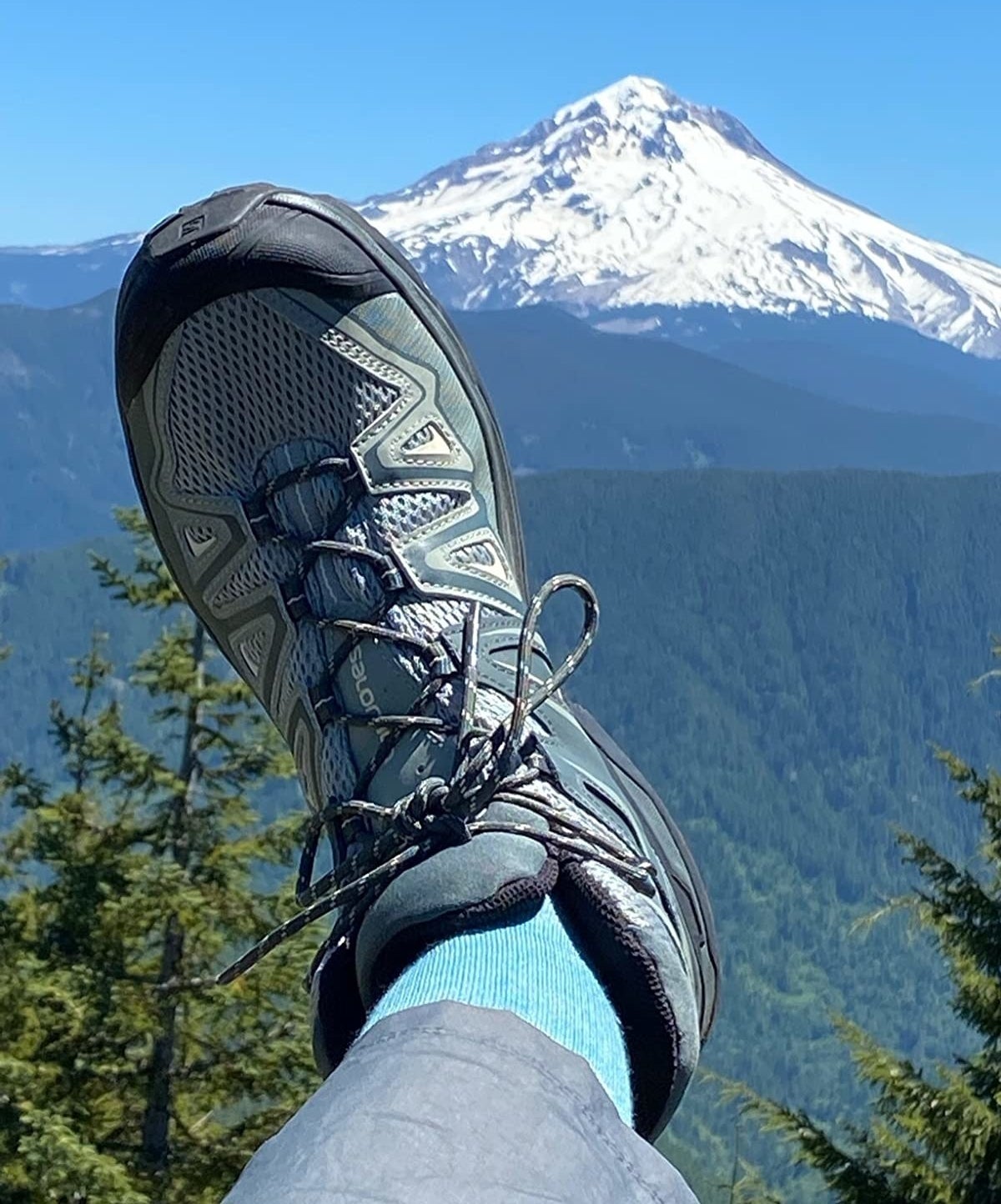 Reviewer wearing the boots with a snowy mountain in the background