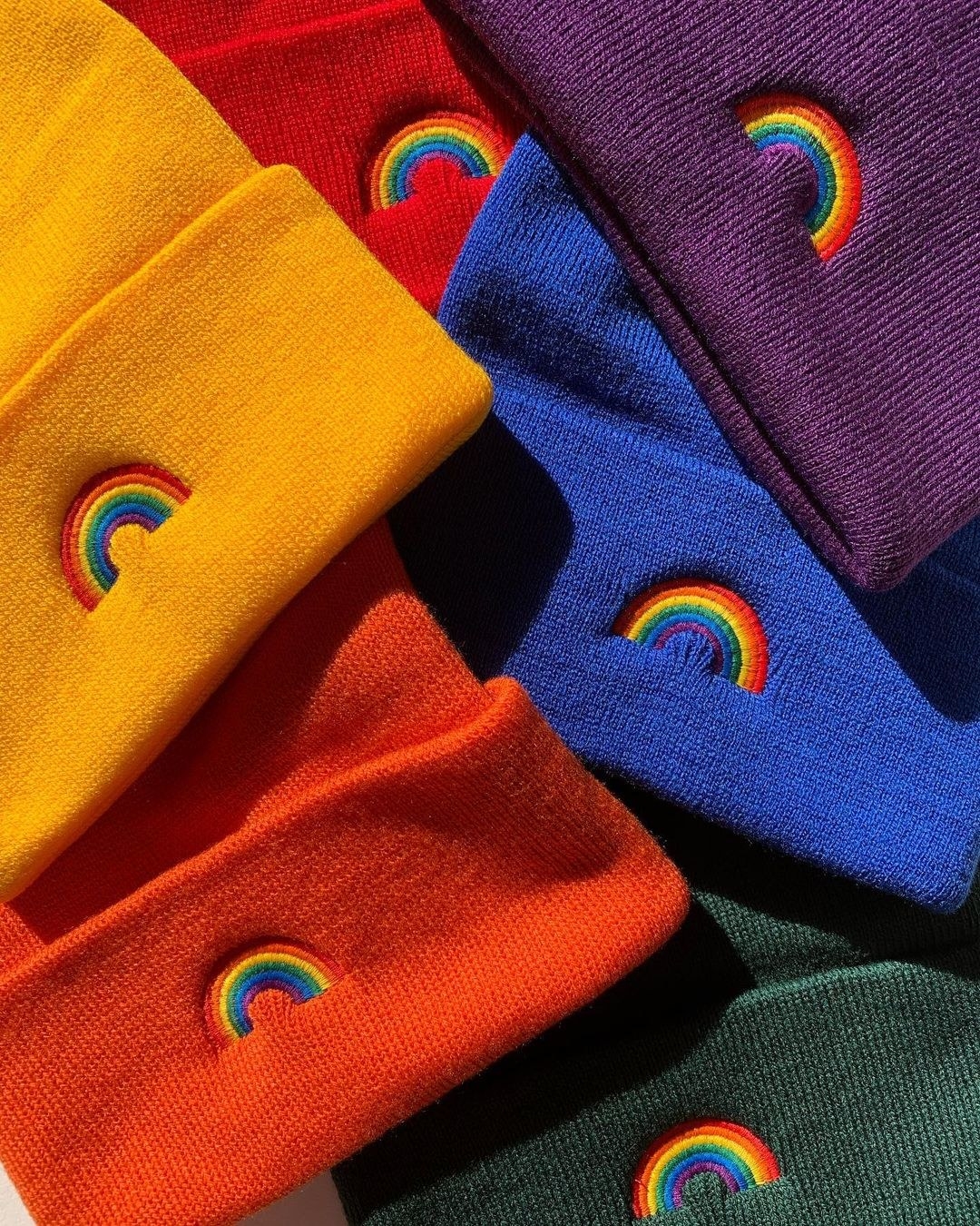 yellow, red orange, green, purple, and blue hates embroidered with a rainbow