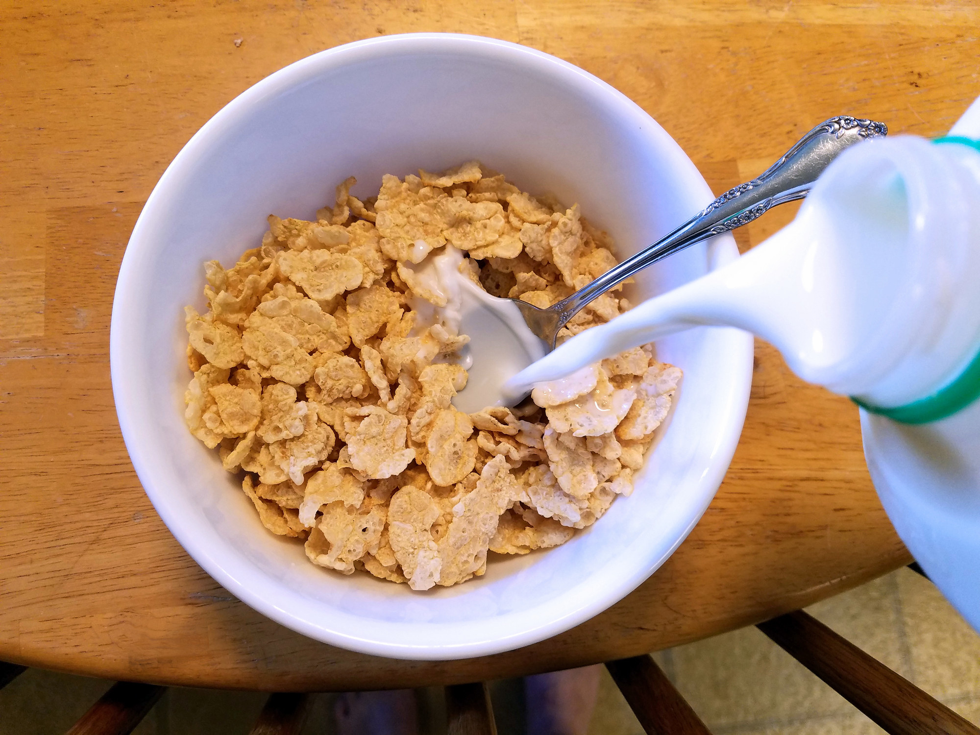 Pouring milk into a bowl of cereal.