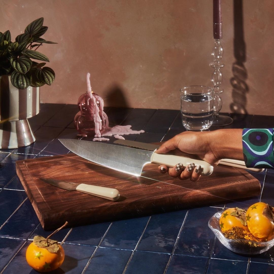 A person holding the chef&#x27;s knife by the handle in front of a cutting board