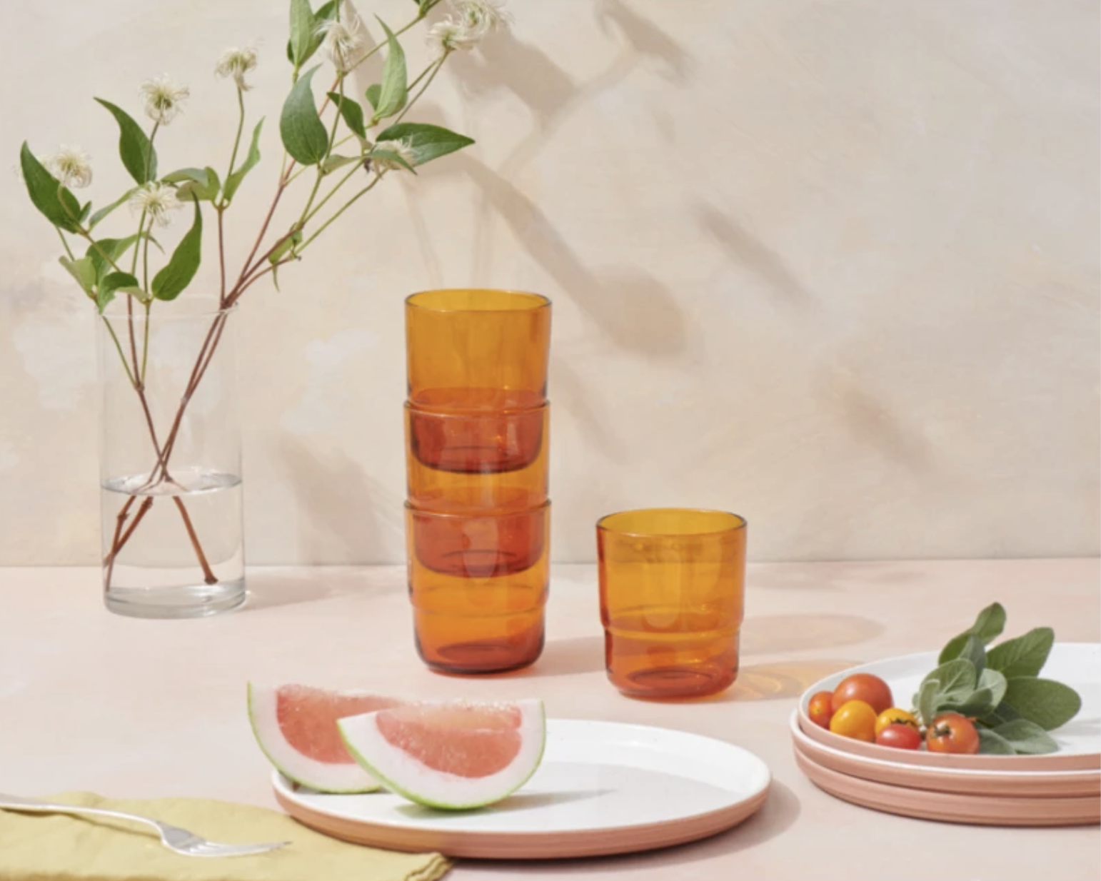 The drinking glasses on a table with plates of fruit in front of them