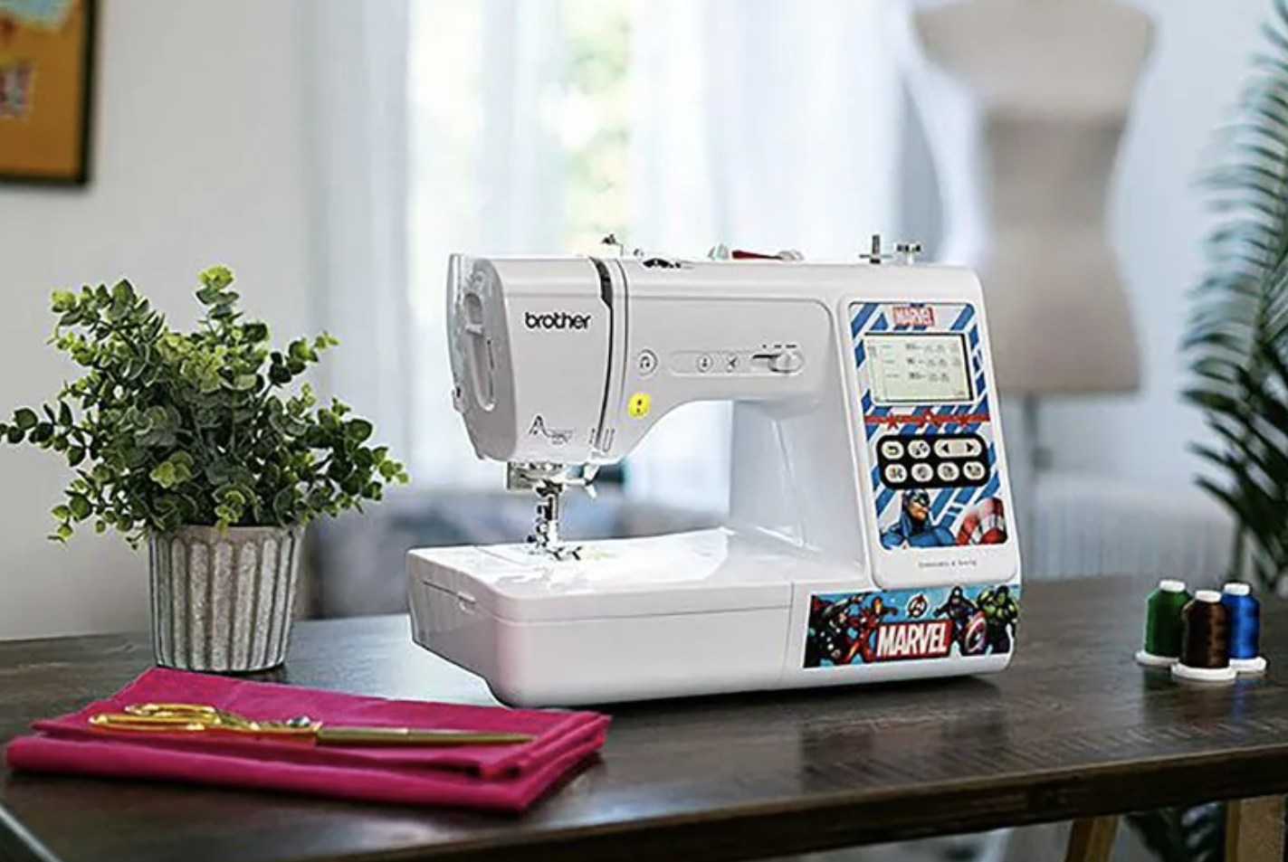 White embroidery machine on table decorated with Marvel characters