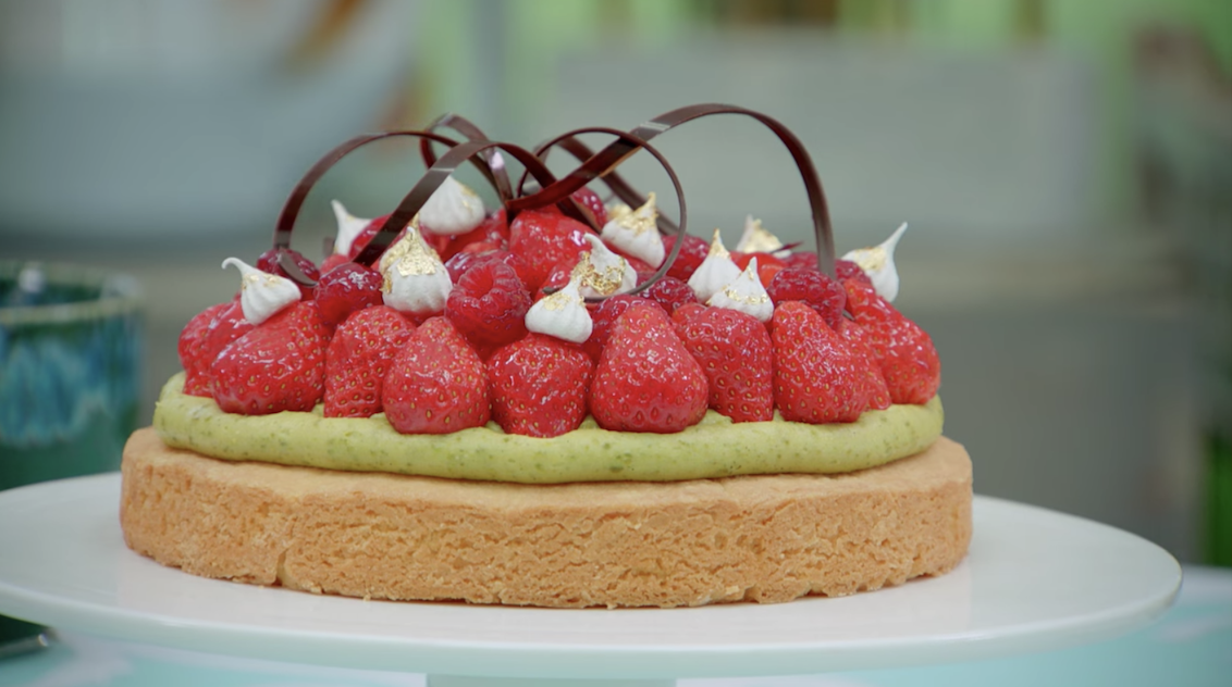 A tart topped with berries, meringue, and chocolate tuiles
