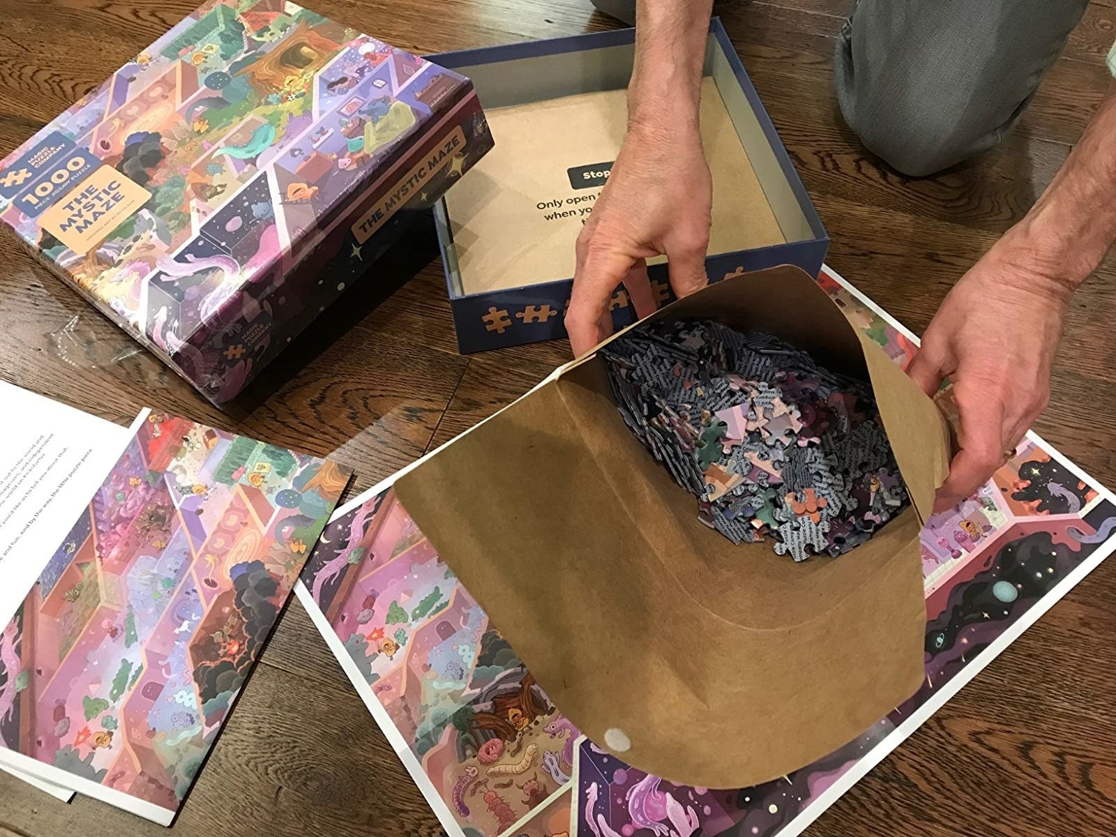 paper bag filled with puzzle pieces next to the box showing a scene of a maze with magical creatures in it